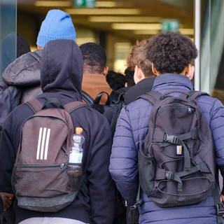 Jugendliche gehen nebeneinander gereiht in das Schulgebäude. Steigt die Gewalt an deutschen Schulen?