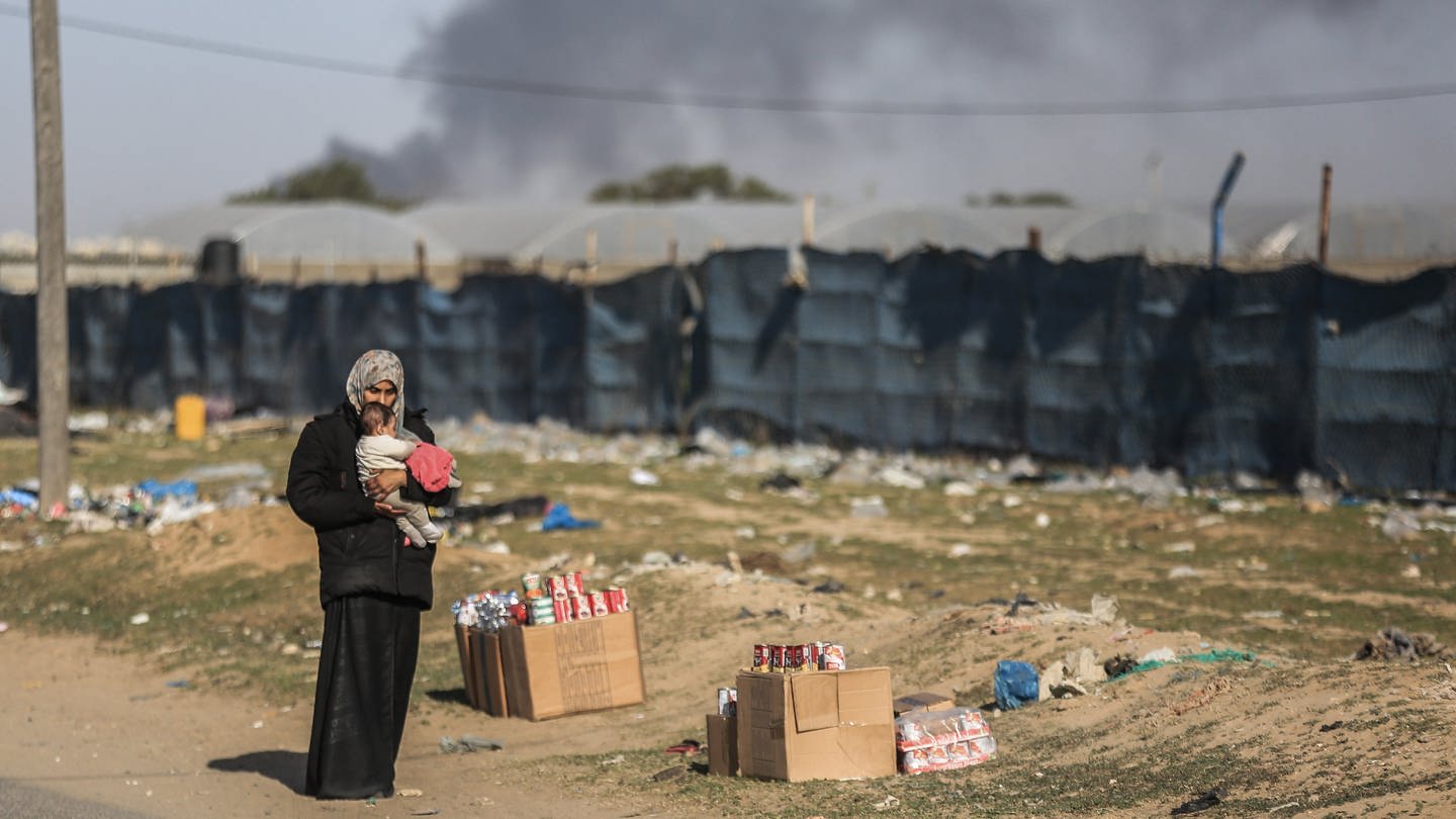 Eine Frau hält ein Kleinkind, während palästinensische Familien aufgrund israelischer Angriffe nach Rafah fliehen.