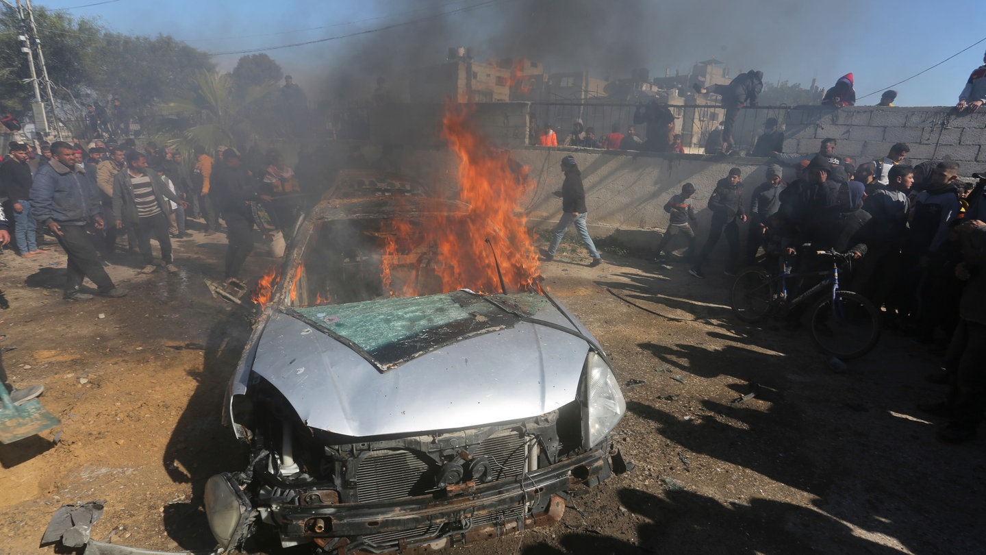 Palästinenser sehen zu wie ein Auto brennt, das von einem israelischen Luftangriff im südlichen Gazastreifen getroffen wurde.