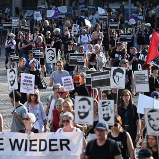 Teilnehmer einer Demo halten im Anschluss an eine Kundgebung für die Opfer des Anschlags von Hanau Plakate mit den Bildern der Opfer.