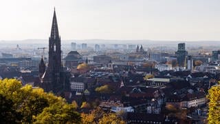 Der Turm des Freiburger Münsters ragt über die Dächer der Innenstadt hinaus, während im Hintergrund Hochhäuser im Stadtteil Weingarten und die Rheinebene zu sehen sind. - In Freiburg wird ein Konsumraum eröffnet. Die Polizei warnt, dass die Stadt von Kokain und Crack "überschwemmt" wird.
