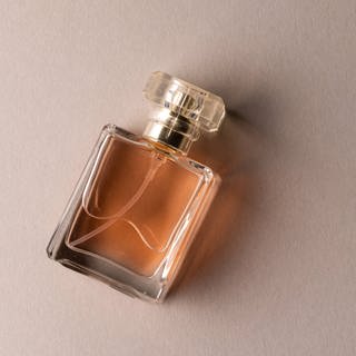 Eine Flasche Parfum vor hellbraunem Hintergrund (Symbolbild)