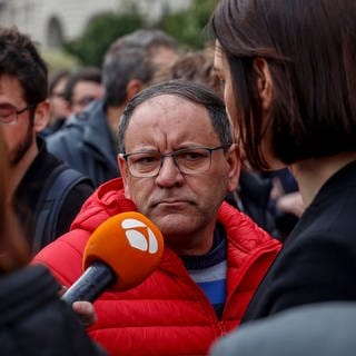 Julián, Hausmeister der Wohnanlage, spricht mit Journalisten nach einer Schweigeminute für die Opfer nach dem Großbrand in einer Wohnanlage im Stadtteil Campanar.