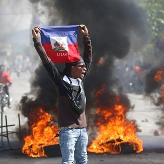 Ein Demonstrant hält eine haitianische Flagge während Protesten für den Rücktritt von Premierminister Henry hoch.