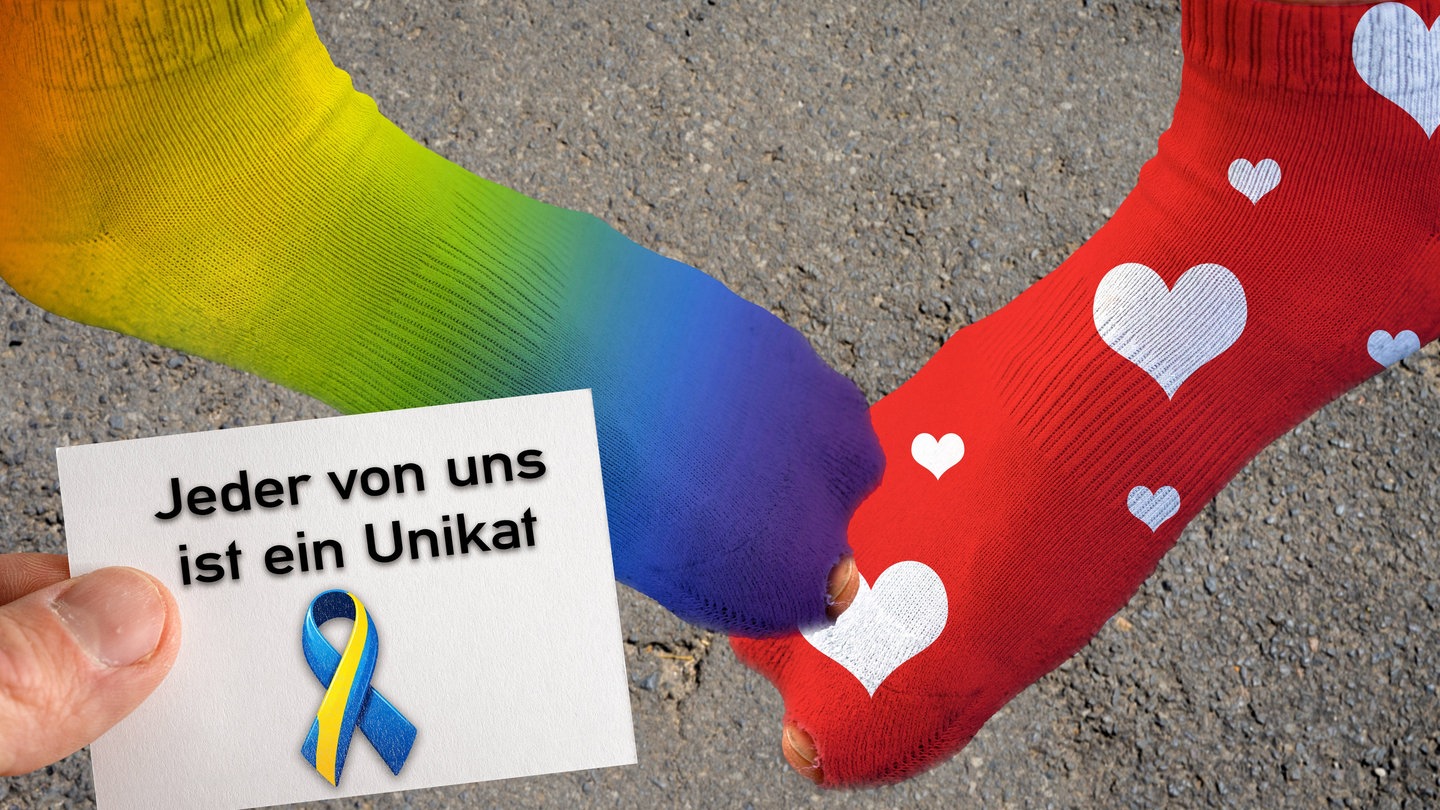 Symbolbild Welt Down Syndrom Tag, Zwei Füße mit verschieden farbigen Socken und eine Hand mit einem Stück Papier mit der Aufschrift: Jeder von uns ist ein Unikat. FOTOMONTAGE