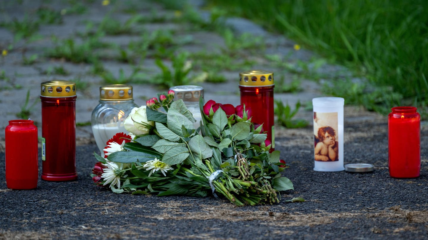 Kerzen und Blumen sind vor einem Seiteneingang des Schulzentrums in Lohr am Main abgelegt.