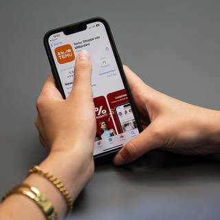 Eine Person hält ein Telefon mit der App Temu in den Händen.