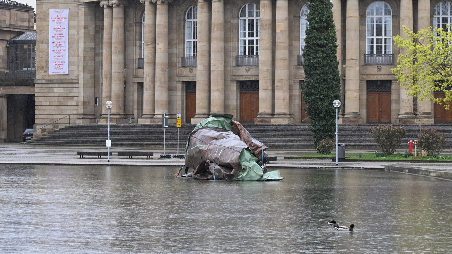 Das durch einen Sturm zerstörte Dach der Stuttgarter Oper ist im Eckensee vor der Oper als Mahnmal gegen den Klimawandel aufgestellt. Auch wegen der EM soll es nun entfernt werden.