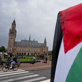 Ein Demonstrant schwenkt die palästinensische Fahne vor dem Friedenspalast, in dem der Internationale Gerichtshof untergebracht ist.