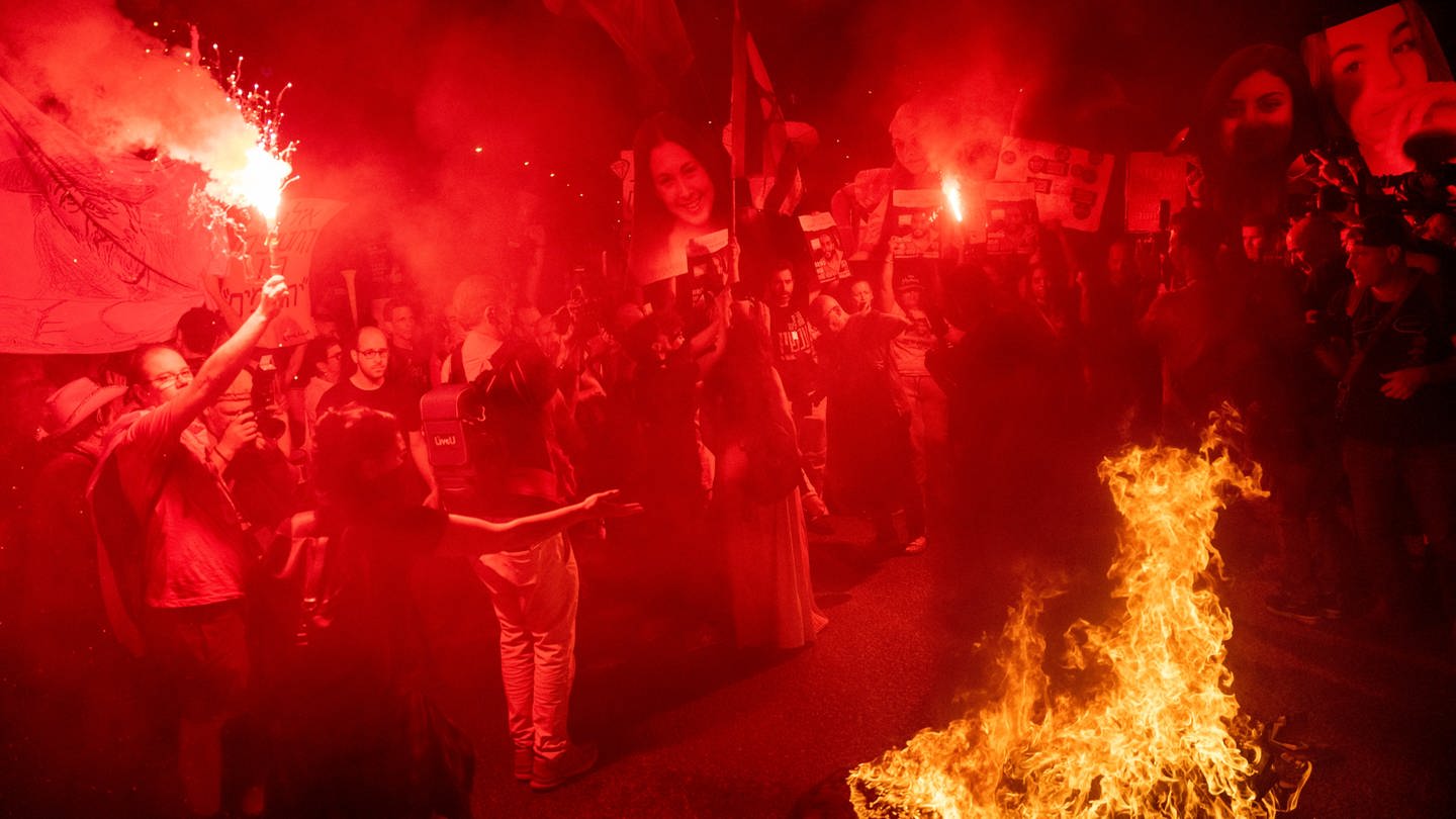 Demonstranten halten Schilder und Bilder von Geiseln, die verbrannt werden, während einer Demonstration gegen die Regierung des israelischen Premiers Netanjahu und fordern die Freilassung von Geiseln, die im Gazastreifen von der militanten Hamas-Gruppe festgehalten werden, in Tel Aviv, Israel.