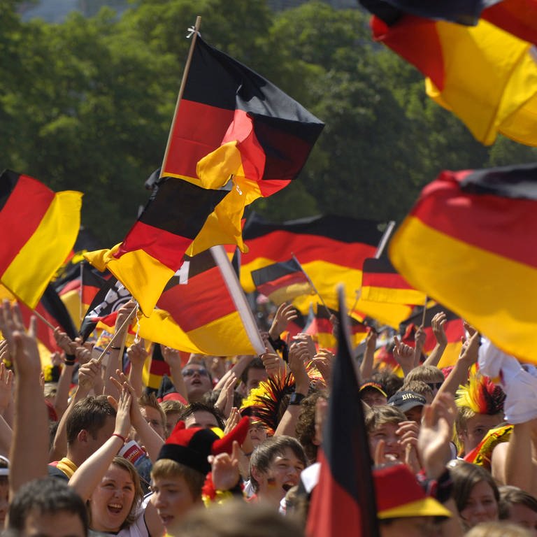Fans schwenken Deutschlandflaggen auf einem Public Viewing. (Archivbild)