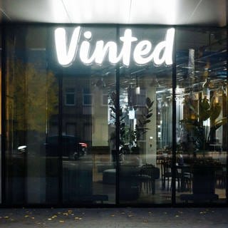 Das Logo von Vinted leuchtet in einem dunklen Bürogebäude.