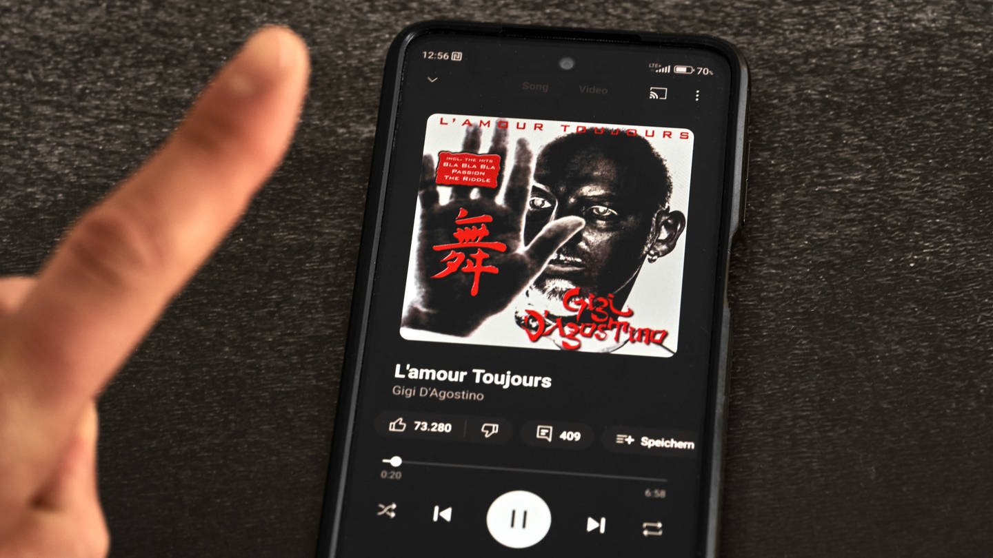 Finger vor Smartphone mit Musik App streamt das Lied 