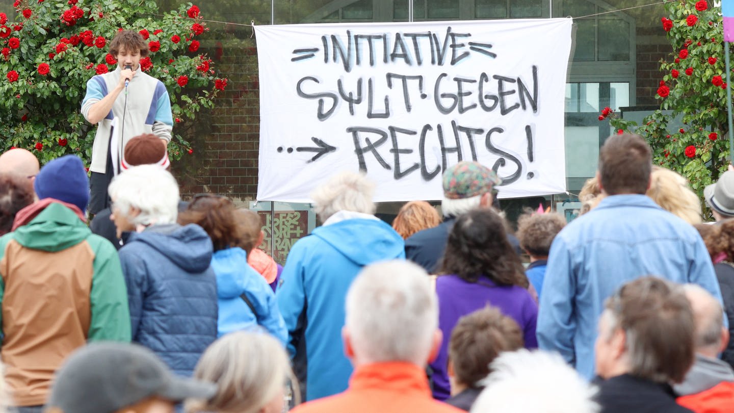 Teilnehmer stehen bei einer Kundgebung vor dem Rathaus in Westerland, wo ein Transparent mit dem Schriftzug „Initiative Sylt gegen Rechts angebracht wurde“.