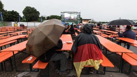 Fußballfans verfolgen am 16.06.2016 beim Public Viewing auf dem Messegelände in Freiburg (Baden-Württemberg) im Regen die EM-Begegnung Deutschland - Polen