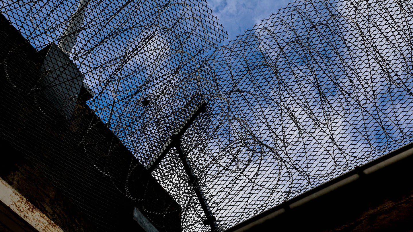 Symbolfoto Gefängnismauer mit Stacheldraht