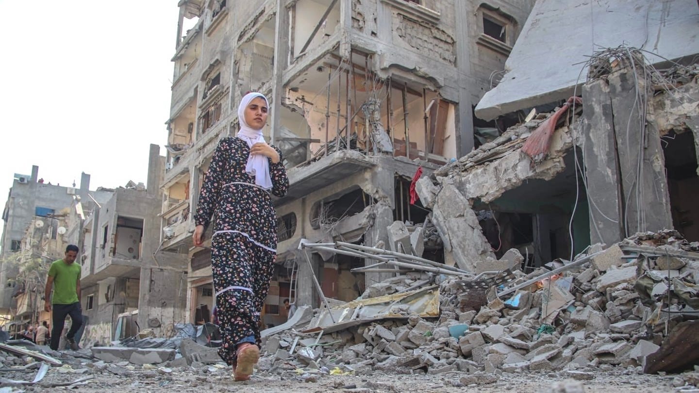 Eine Frau geht nach der Zerstörung von Wohntürmen in Bureij auf der Straße. Die UN wirft sowohl Israel als auch der Hamas Kriegsverbrechen vor.