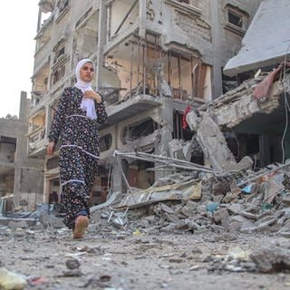 Eine Frau geht nach der Zerstörung von Wohntürmen in Bureij auf der Straße. Die UN wirft sowohl Israel als auch der Hamas Kriegsverbrechen vor.