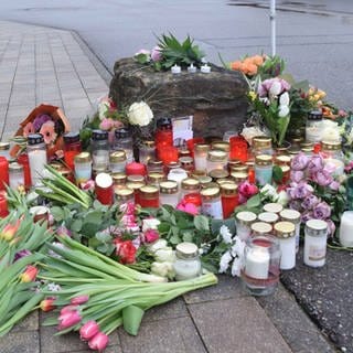 Blumen und Kerzen zum Gedenken an das Opfer liegen vor einer Schule.