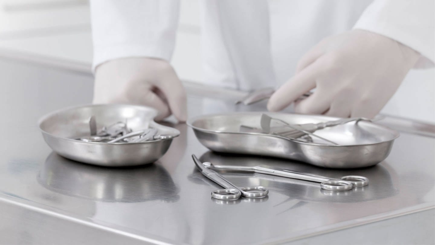 Ein Chirurg stützt sich auf einem OP-Tisch mit Instrumenten ab.