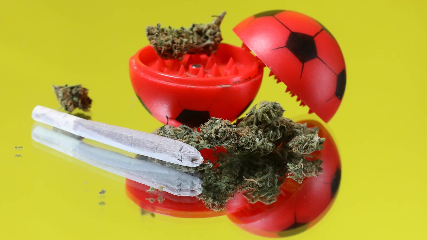 Ein Grinder in Fußballform mit Cannabis und einem Joint