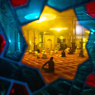 Gläubige, die an einem Gebet anlässlich des Islamischen Opferfestes «Eid al-Adha» teilnehmen, sind durch das bunte Fensterglas in einer Moschee zu sehen. Das Opferfest Eid al-Adha gilt als wichtigste islamische Feier