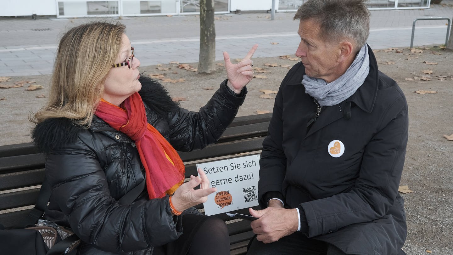 Menschen unterhalten sich auf Zuhörbank