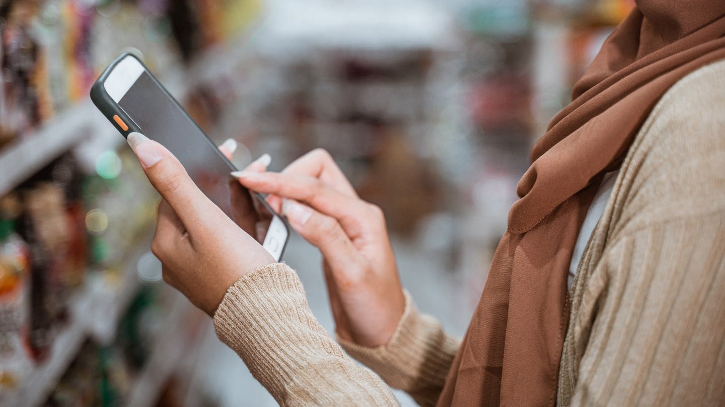 Ein Mädchen bedient ihr Smartphone im Supermarkt