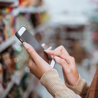 Ein Mädchen bedient ihr Smartphone im Supermarkt