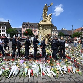 Polizisten stehen auf dem Marktplatz vor einem Gedenkplatz für einen bei einer Messerattacke getöteten Polizisten. Eine Woche zuvor wurde auf dem Platz ein Polizist bei einem Messerangriff getötet.