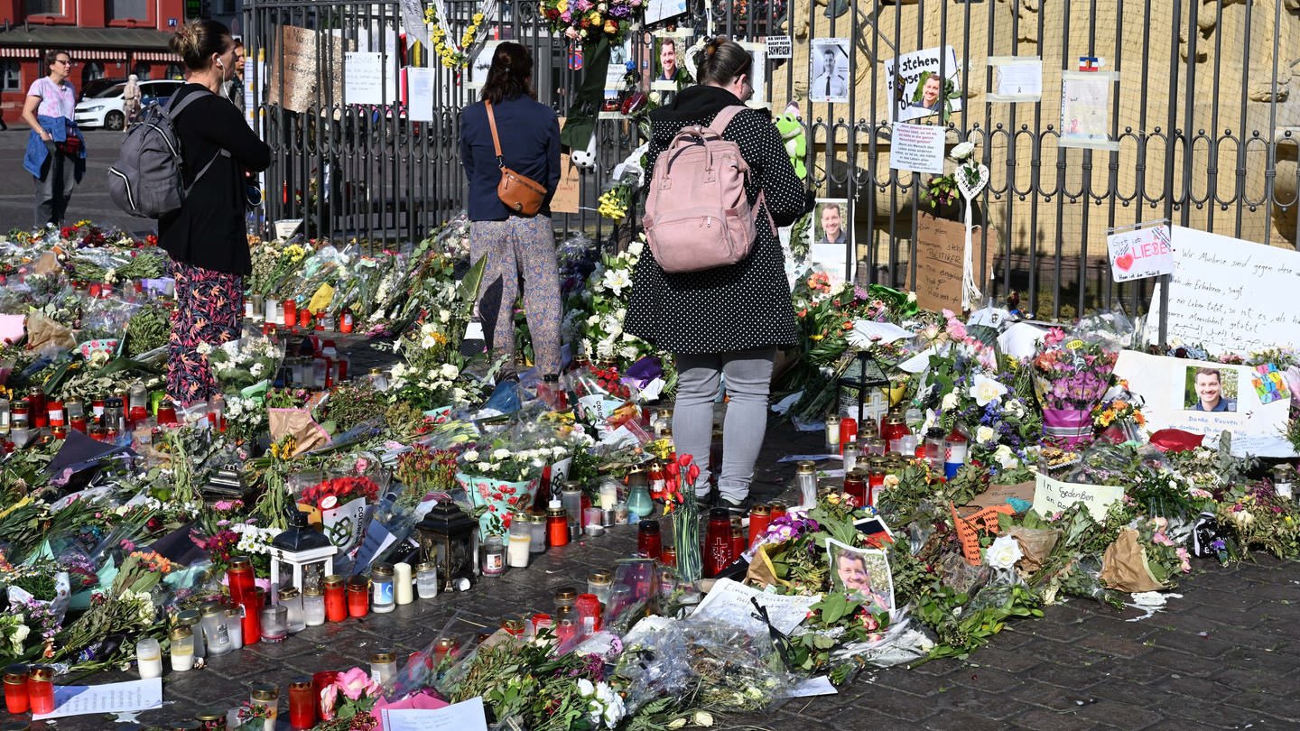 Blumen und Kerzen liegen auf dem Marktplatz in Mannheim zum Gedenken an einen getöteten Polizisten Rouven Laur.