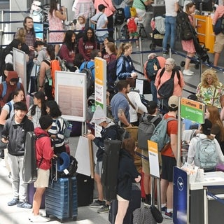 Urlauber vor der Gepackaufgaben am Flughafen: Flüge sind innerhalb der Ferien meist günstiger.