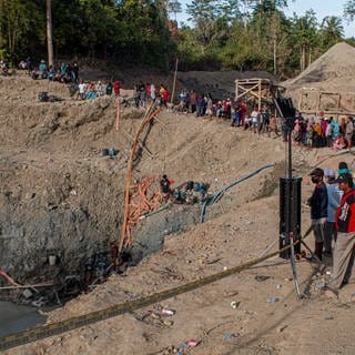 Menschen beobachten 2021, wie Rettungskräfte in Indonesien nach Opfern in einer eingestürzten Goldmine suchen. Den Einsturz hatte ein Erdrutsch ausgelöst. (Symbolbild)