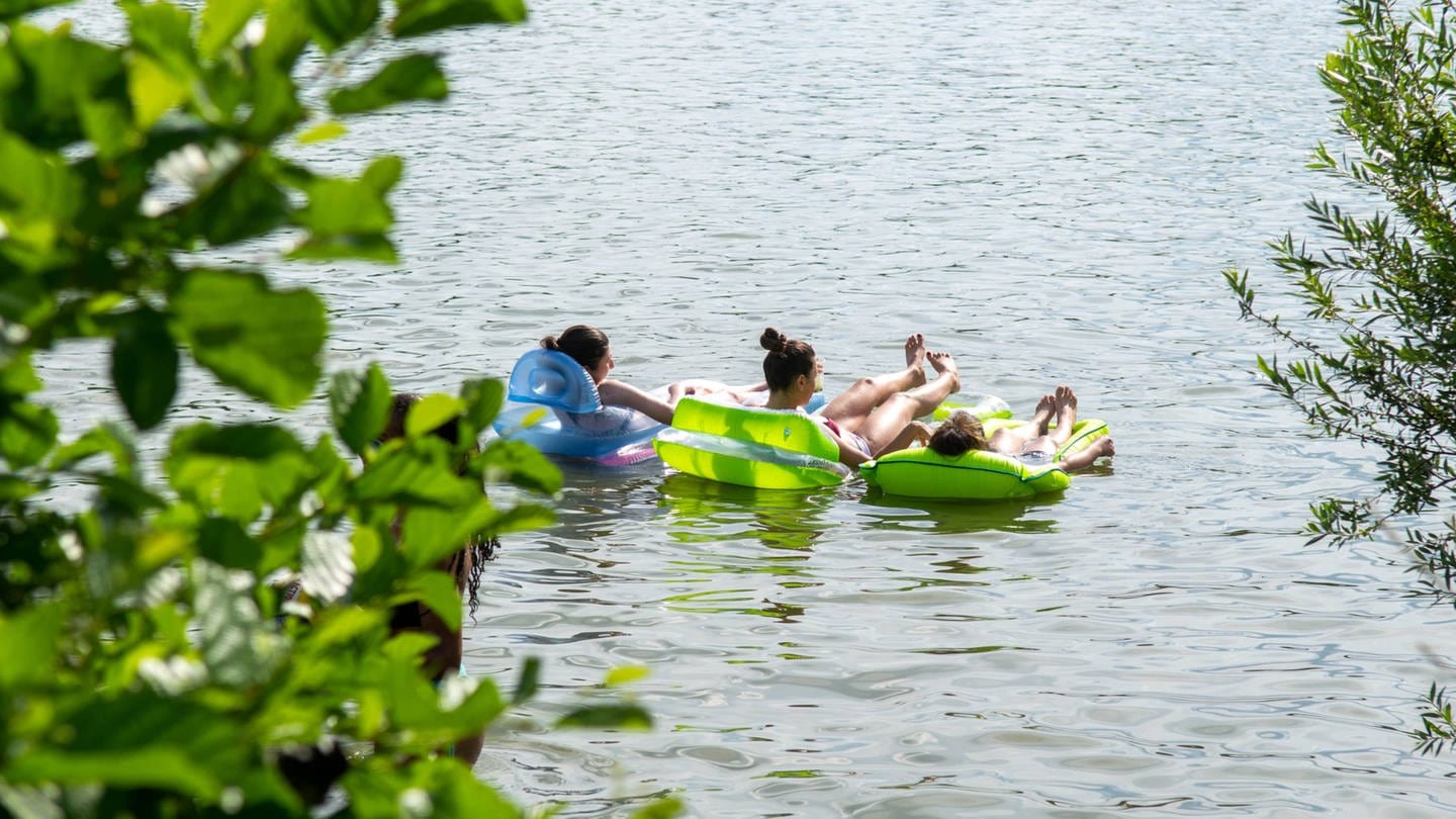 Junge Menschen auf Luftmatratzen in einem See in Baden-Württemberg.