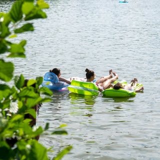 Junge Menschen auf Luftmatratzen in einem See in Baden-Württemberg.