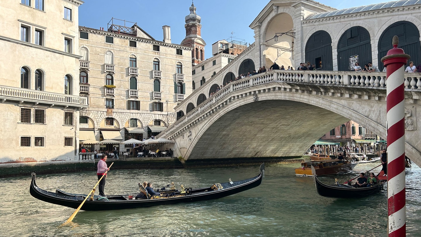 Eine Gondel mit Touristen vor der Rialto-Brücke im Zentrum von Venedig.