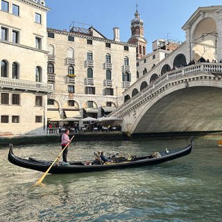 Eine Gondel mit Touristen vor der Rialto-Brücke im Zentrum von Venedig.