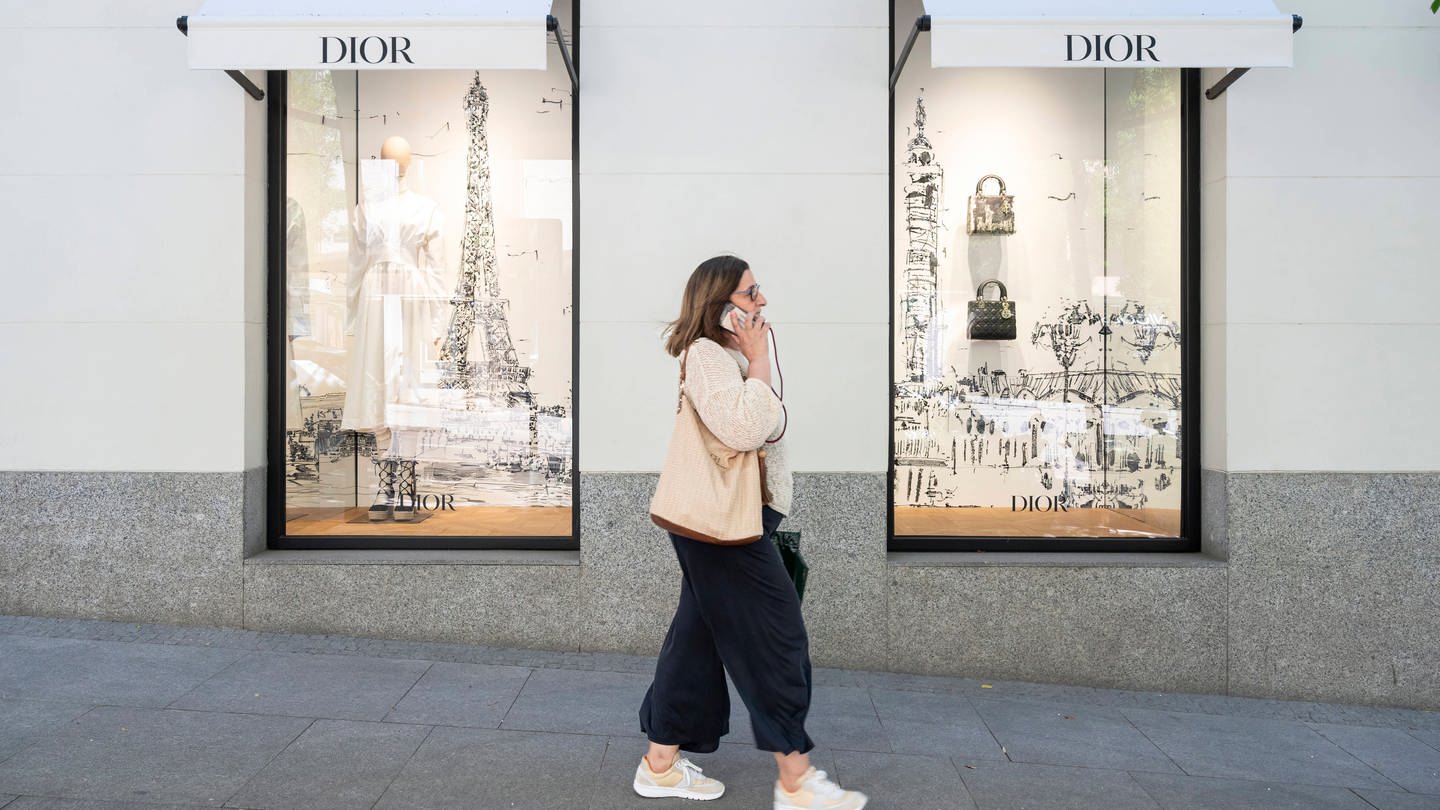 Eine Frau läuft an Schaufenstern von einem Dior-Laden vorbei - Gegen Dior und Armani wird jetzt wegen möglicher Ausbeitung von Mitarbeitern ermittelt.