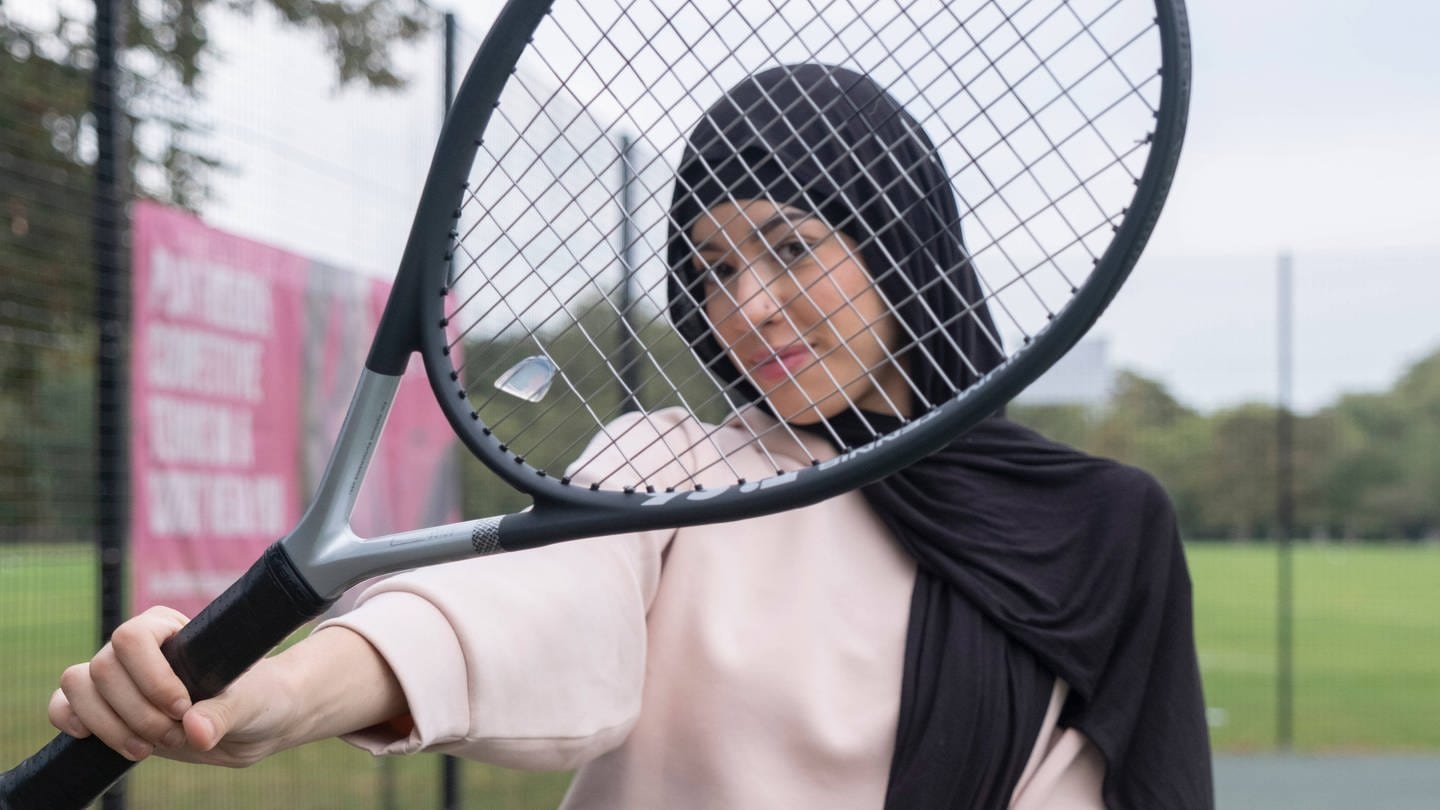 Ein Mädchen mit Tennisschläger trägt einen Hijab