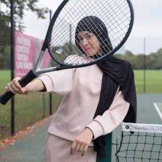 Ein Mädchen mit Tennisschläger trägt einen Hijab