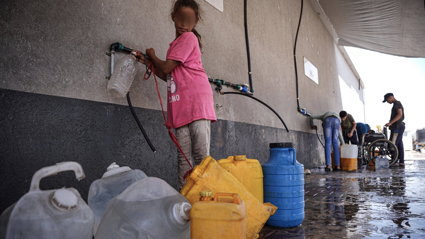 Ein Mädchen im Gazastreifen füllt Wasser in Kanister