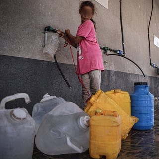 Ein Mädchen im Gazastreifen füllt Wasser in Kanister