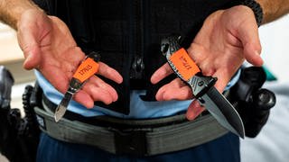 Symbolbild: Waffenverbotszone - Ein Bundespolizist zeigt am Hauptbahnhof sichergestellte Messer.