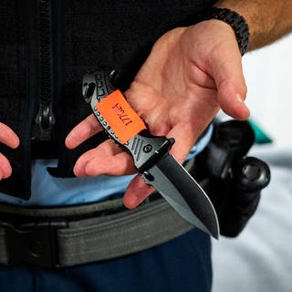 Symbolbild: Waffenverbotszone - Ein Bundespolizist zeigt am Hauptbahnhof sichergestellte Messer.