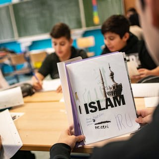 Ein Schüler öffnet seinen seinen selbst gestalteten Ordner beim Islamunterricht - in Baden-Württemberg soll er ausgebaut werden (Symbolbild)