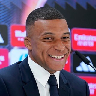 Der Franzose Kylian Mbappé lächelt während einer Pressekonferenz.