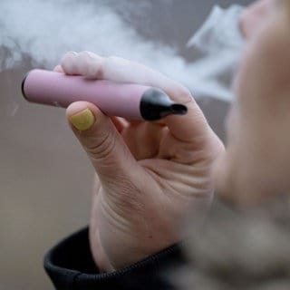 Eine Frau raucht eine E-Zigarette. Baden-Württemberg will Einweg-E-Zigaretten - Vapes -  verbieten.