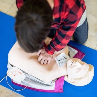 Ein Junge führt eine Herzdruckmassage an einer Simulationspuppe durch. 