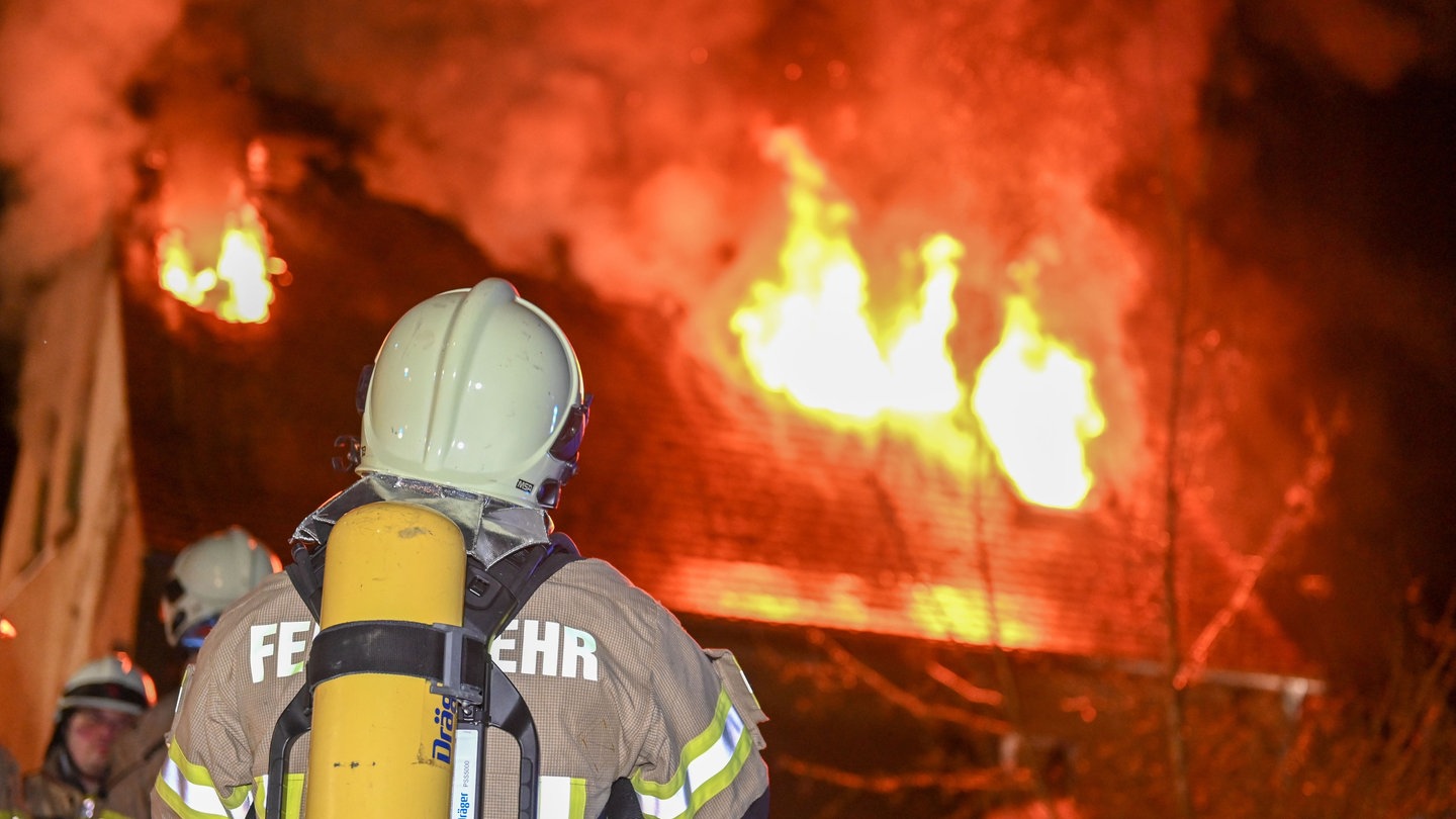 Feuerwehrmann im Einsatz vor einem brennenden Haus - Forschende haben eine selbstkuehlende Feuerwehrjacke entwickelt