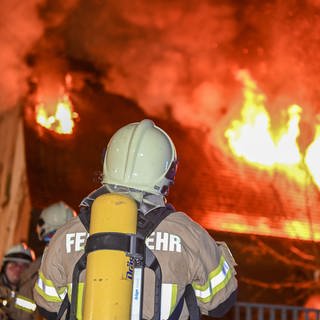 Feuerwehrmann im Einsatz vor einem brennenden Haus - Forschende haben eine selbstkuehlende Feuerwehrjacke entwickelt